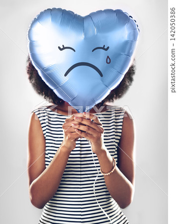 Black woman, emoji and sad heart balloon in studio for heartbreak, depression or emotional on isolated white background. Icon, tear and female model with blue object for lonely, breakup or crying 142050386