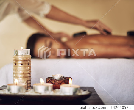 Candles, hot stones and wax light at a spa for lomi lomi massage, healing or luxury treatment therapy. Health, aromatherapy and wellness products for calm, zen or peaceful atmosphere at natural salon Candles, hot stones and wax light at a spa for lomi lomi massage, healing or luxury treatment therapy. Health, aromatherapy and wellness products for calm, zen or peaceful atmosphere at natural salon 142050523