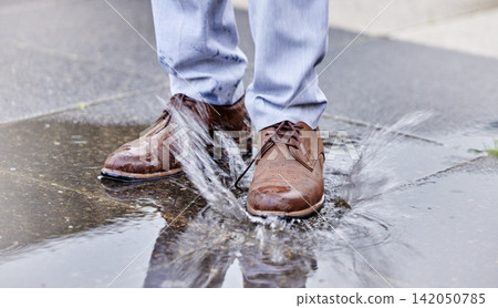 Person, puddle and shoe stepping in water on ground for commute to work, job or business. Splash, street and wet footwear with employee in city for travel, progress or weather resistant attitude Person, puddle and shoe stepping in water on ground for commute to work, job or business. Splash, street and wet footwear with employee in city for travel, progress or weather resistant attitude 142050785