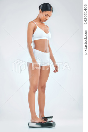 Woman, fitness and checking weight with scale for diet, results or measurement on a gray studio background. Female person or model with underwear on weighing machine for BMI, body mass or wellness Woman, fitness and checking weight with scale for diet, results or measurement on a gray studio background. Female person or model with underwear on weighing machine for BMI, body mass or wellness 142051406