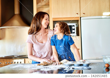 Parent, child and flour in kitchen for baking with breakfast food, funny joke and dough. Girl, mom and countertop in family home for cooking meal with childhood memory, happy together and muffins Parent, child and flour in kitchen for baking with breakfast food, funny joke and dough. Girl, mom and countertop in family home for cooking meal with childhood memory, happy together and muffins 142051485