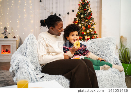 Mother son enjoying Christmas holiday eating sweet donuts Mother son enjoying Christmas holiday eating sweet donuts 142051486