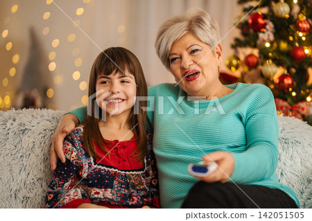 Grandmother and granddaughter watching TV together during Christmas holiday 142051505