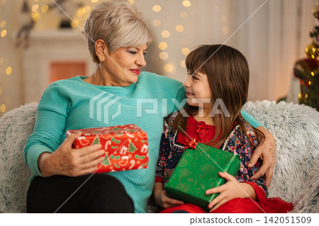 Grandmother and granddaughter exchanging Christmas gifts during holiday season 142051509