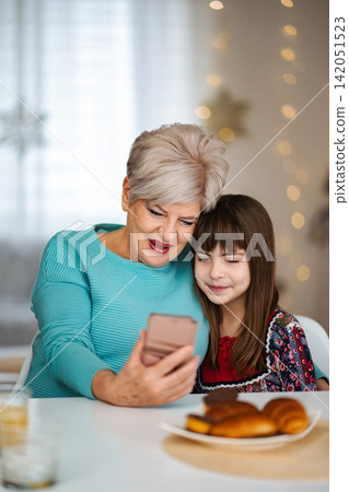 Grandmother and granddaughter bonding using smartphone during Christmas holiday Grandmother and granddaughter bonding using smartphone during Christmas holiday 142051523