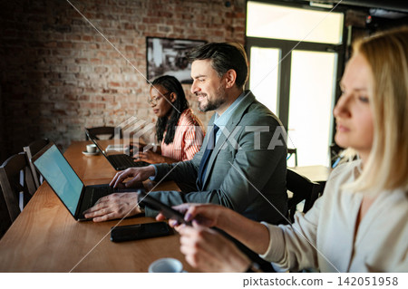 Diverse business professionals working together on laptops in coworking space Diverse business professionals working together on laptops in coworking space 142051958