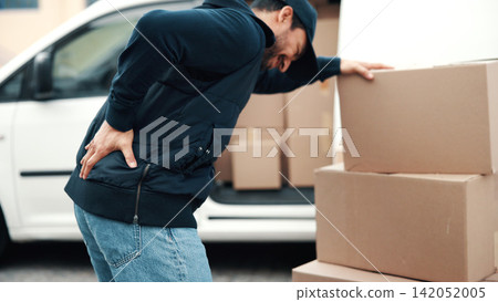Back pain, boxes and delivery man by van for courier transport, shipping and distribution. Burnout, person and cargo parcel by vehicle with muscle fatigue, heavy lifting or strain at package drop off Back pain, boxes and delivery man by van for courier transport, shipping and distribution. Burnout, person and cargo parcel by vehicle with muscle fatigue, heavy lifting or strain at package drop off 142052005