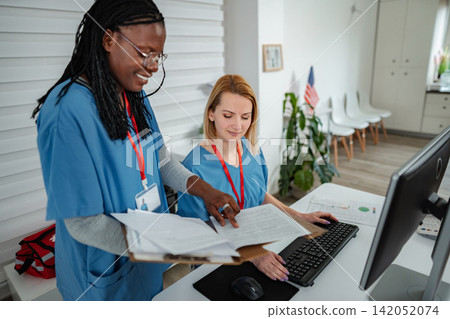Nurses collaborating in modern clinic office working on computer Nurses collaborating in modern clinic office working on computer 142052074