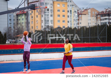 Two women playing basketball on urban outdoor court 142052085