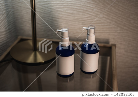 客房的邊桌上擺放著一排沒有標籤的瓶子,一盞黃銅燈照亮了它們。 客房的邊桌上擺放著一排沒有標籤的瓶子,一盞黃銅燈照亮了它們。 142052103