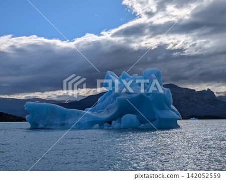 Blue Iceberg Floating Below Heavy Patagonian Clouds Blue Iceberg Floating Below Heavy Patagonian Clouds 142052559