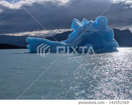 Blue Iceberg Surrounded by Sunlit Ripples in Canal Upsala Blue Iceberg Surrounded by Sunlit Ripples in Canal Upsala 142052560