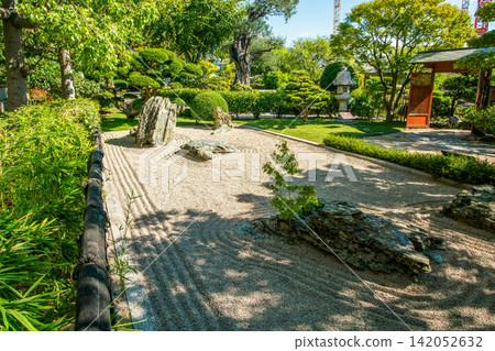 Princess Grace Japanese Garden in Monaco in summer and pond and pavilion, carps KOI and stone lantern in water . Red flowers of lantana (from America continent) Princess Grace Japanese Garden in Monaco in summer and pond and pavilion, carps KOI and stone lantern in water . Red flowers of lantana (from America continent) 142052632