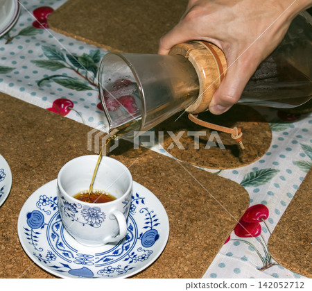 Fresh Filter Coffee Poured from Glass Carafe into Patterned Cup Fresh Filter Coffee Poured from Glass Carafe into Patterned Cup 142052712