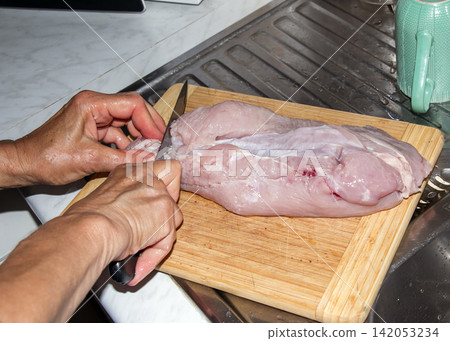 Trimming Raw Poultry Meat with Kitchen Knife on Cutting Board Trimming Raw Poultry Meat with Kitchen Knife on Cutting Board 142053234