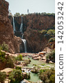 Tall Cascading Waterfall Surrounded by Cliffs Tall Cascading Waterfall Surrounded by Cliffs 142053242
