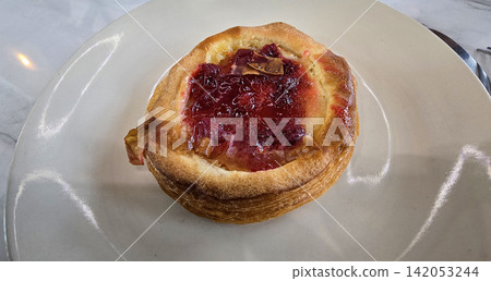 Golden flaky danish pastry jam tart puff served on a white plate with a fork on a marble table, ideal for breakfast, brunch, or dessert photography. Warm, homemade, sweet and appetizing bakery Golden flaky danish pastry jam tart puff served on a white plate with a fork on a marble table, ideal for breakfast, brunch, or dessert photography. Warm, homemade, sweet and appetizing bakery 142053244