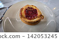 Golden flaky danish pastry jam tart puff served on a white plate with a fork on a marble table, ideal for breakfast, brunch, or dessert photography. Warm, homemade, sweet and appetizing bakery 142053245