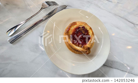 Golden flaky danish pastry jam tart puff served on a white plate with a fork on a marble table, ideal for breakfast, brunch, or dessert photography. Warm, homemade, sweet and appetizing bakery Golden flaky danish pastry jam tart puff served on a white plate with a fork on a marble table, ideal for breakfast, brunch, or dessert photography. Warm, homemade, sweet and appetizing bakery 142053246