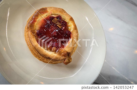 Golden flaky danish pastry jam tart puff served on a white plate with a fork on a marble table, ideal for breakfast, brunch, or dessert photography. Warm, homemade, sweet and appetizing bakery Golden flaky danish pastry jam tart puff served on a white plate with a fork on a marble table, ideal for breakfast, brunch, or dessert photography. Warm, homemade, sweet and appetizing bakery 142053247