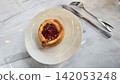 Golden flaky danish pastry jam tart puff served on a white plate with a fork on a marble table, ideal for breakfast, brunch, or dessert photography. Warm, homemade, sweet and appetizing bakery 142053248