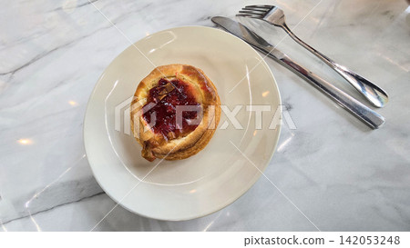 Golden flaky danish pastry jam tart puff served on a white plate with a fork on a marble table, ideal for breakfast, brunch, or dessert photography. Warm, homemade, sweet and appetizing bakery Golden flaky danish pastry jam tart puff served on a white plate with a fork on a marble table, ideal for breakfast, brunch, or dessert photography. Warm, homemade, sweet and appetizing bakery 142053248
