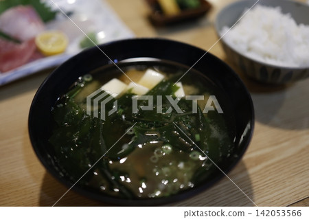 Miso soup with plenty of seaweed. Contains tofu. Served in a black bowl. Japanese food. Miso soup with plenty of seaweed. Contains tofu. Served in a black bowl. Japanese food. 142053566