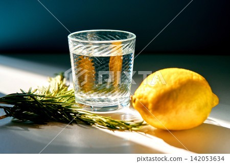 Glass of water with lemon and rosemary for hydration Glass of water with lemon and rosemary for hydration 142053634