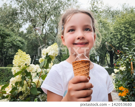 Happy Young Girl Smiling with Chocolate Ice Cream Cone in a Summer Park Happy Young Girl Smiling with Chocolate Ice Cream Cone in a Summer Park 142053680