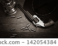 Antique Revolver with Ammunition, Cowboy Hat and Lantern on Wooden Table 142054384
