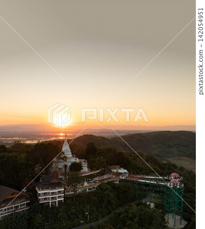 Skywalk and temple complex silhouetted against the evening sky. The sunset creates a warm backdrop over the surrounding hills. Skywalk and temple complex silhouetted against the evening sky. The sunset creates a warm backdrop over the surrounding hills. 142054951