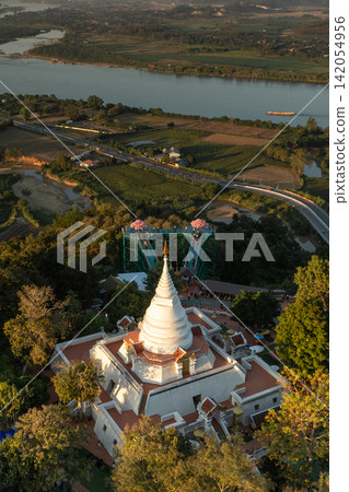 Aerial view of skywalk and temple overlooking the Mekong River, composition shows temple, forest, farmland, distant hills. Aerial view of skywalk and temple overlooking the Mekong River, composition shows temple, forest, farmland, distant hills. 142054956