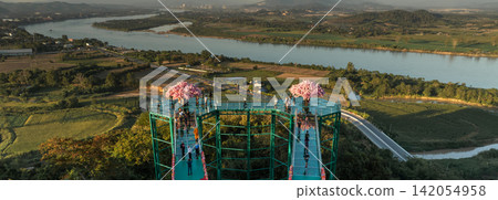 Skywalk at Wat Phrathat Pha Ngao above the Mekong River landscape. The Buddhist temple and riverside setting reflect northern Thai heritage. Skywalk at Wat Phrathat Pha Ngao above the Mekong River landscape. The Buddhist temple and riverside setting reflect northern Thai heritage. 142054958