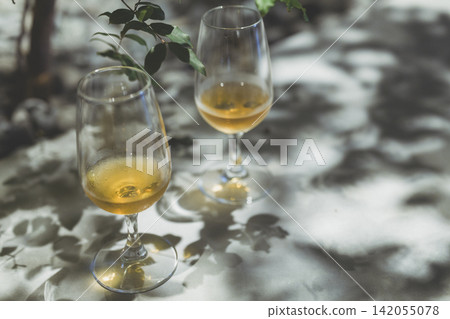 桌上擺放著幾隻酒杯,植物投下斑駁的影子。 桌上擺放著幾隻酒杯,植物投下斑駁的影子。 142055078