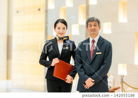 經理和女員工站在飯店大廳裡。 經理和女員工站在飯店大廳裡。 142055186