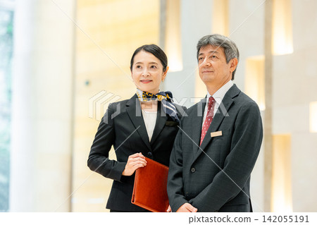 經理和女員工站在飯店大廳裡。 經理和女員工站在飯店大廳裡。 142055191