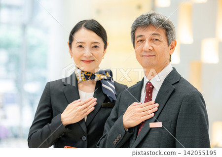經理和女員工站在飯店大廳裡。 經理和女員工站在飯店大廳裡。 142055195