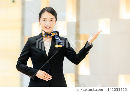 一位女士面帶微笑地站在飯店裡。 一位女士面帶微笑地站在飯店裡。 142055213
