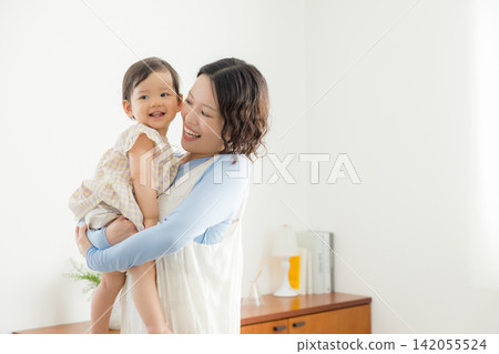 一位母親抱著她一歲的女兒。 一位母親抱著她一歲的女兒。 142055524