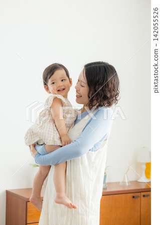 一位母親抱著她一歲的女兒。 一位母親抱著她一歲的女兒。 142055526
