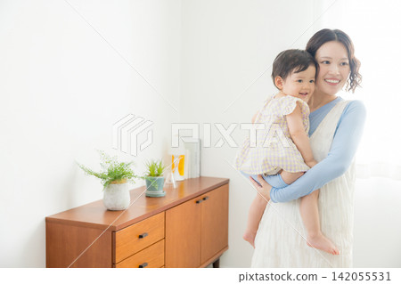 一位母親抱著她一歲的女兒。 一位母親抱著她一歲的女兒。 142055531