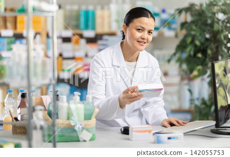 Female pharmacist updating stock inventory on pharmacy computer Female pharmacist updating stock inventory on pharmacy computer 142055753