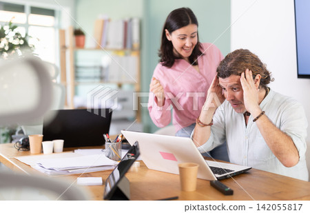 Happy male and female colleagues cheering at successful result on laptop Happy male and female colleagues cheering at successful result on laptop 142055817