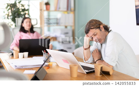 Tired man fell asleep at his desk in office Tired man fell asleep at his desk in office 142055833