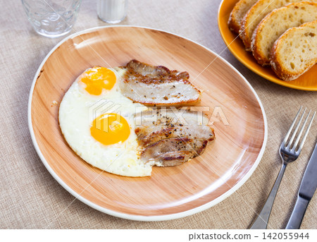 Appetizing breakfast with scrambled eggs and juicy bacon closeup Appetizing breakfast with scrambled eggs and juicy bacon closeup 142055944