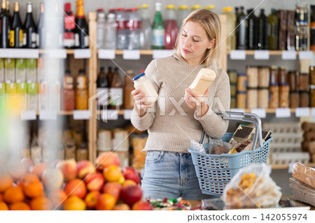 Young woman choosing mayonnaise in grocery store Young woman choosing mayonnaise in grocery store 142055974