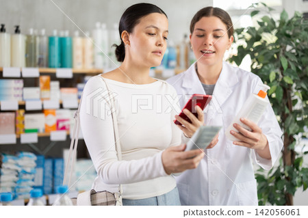 Asian female client choosing cream or skin care product in pharmacy and scan QR code on label, young woman pharmacist consulting and offering variety of goods to customer Asian female client choosing cream or skin care product in pharmacy and scan QR code on label, young woman pharmacist consulting and offering variety of goods to customer 142056061