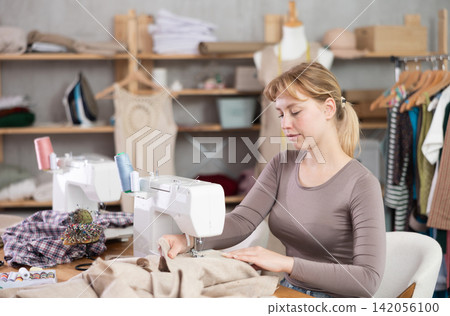 Woman tailor working at sewing machine Woman tailor working at sewing machine 142056100