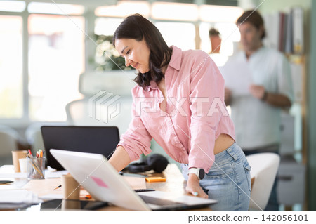 Middle-aged woman drawing on paper while working at office desk Middle-aged woman drawing on paper while working at office desk 142056101