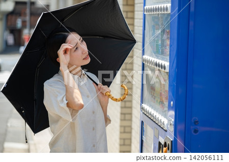 A woman buying a drink while holding a parasol. A woman buying a drink while holding a parasol. 142056111